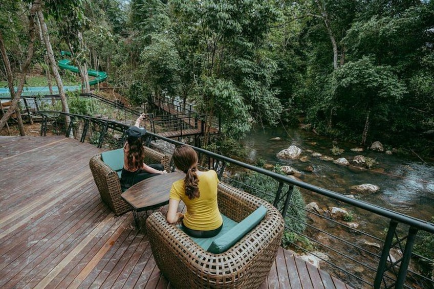 Una terraza de madera con muebles de mimbre con vistas a un río. 2