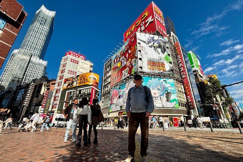 A busy urban street with tall buildings, pedestrians, and a clear blue sky. 2