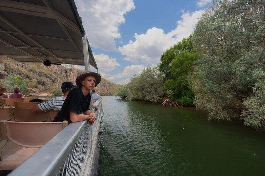 A river with a boat, passengers, and trees along the banks. 3
