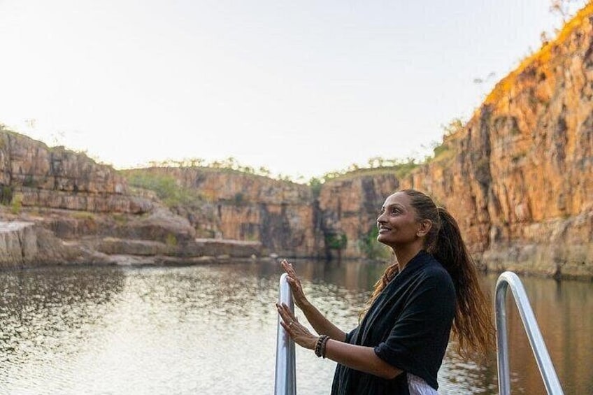A person standing by a body of water with cliffs in the background. 2