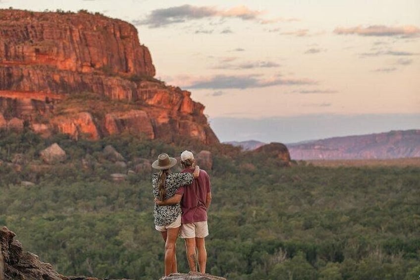 A couple standing on a rock overlooking a canyon with a mountain in the background. 2