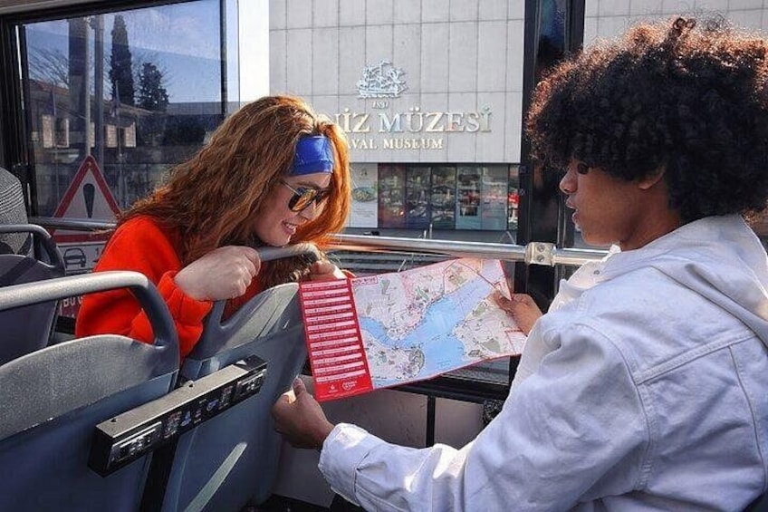 Two people sitting on a bus, one holding a map. 4