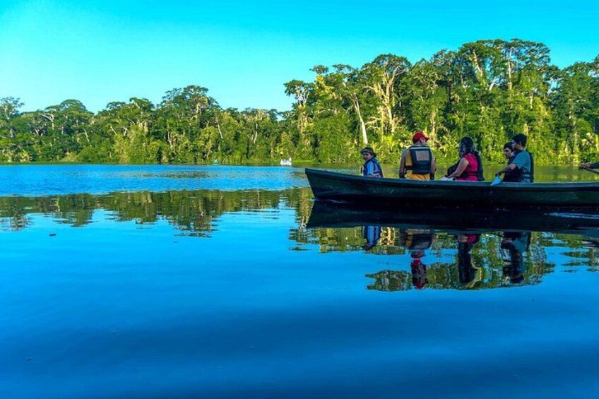 A calm lake with a boat carrying four people. 1