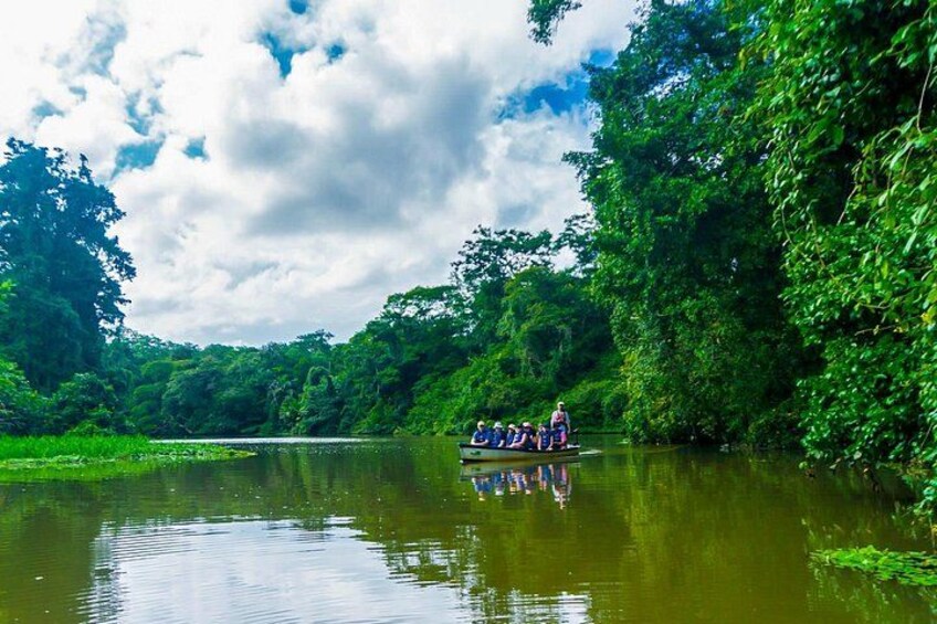 A group of people in a boat on a calm river surrounded by lush greenery. 4