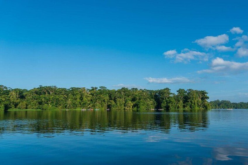 A calm lake with a forested island and clear blue sky. 5