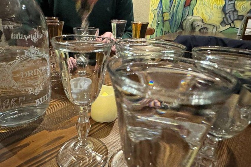 A table with a bottle labeled 'DRINKS' and several empty glasses. 5