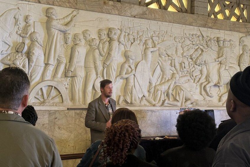 A group of people observing a detailed stone relief sculpture. 3