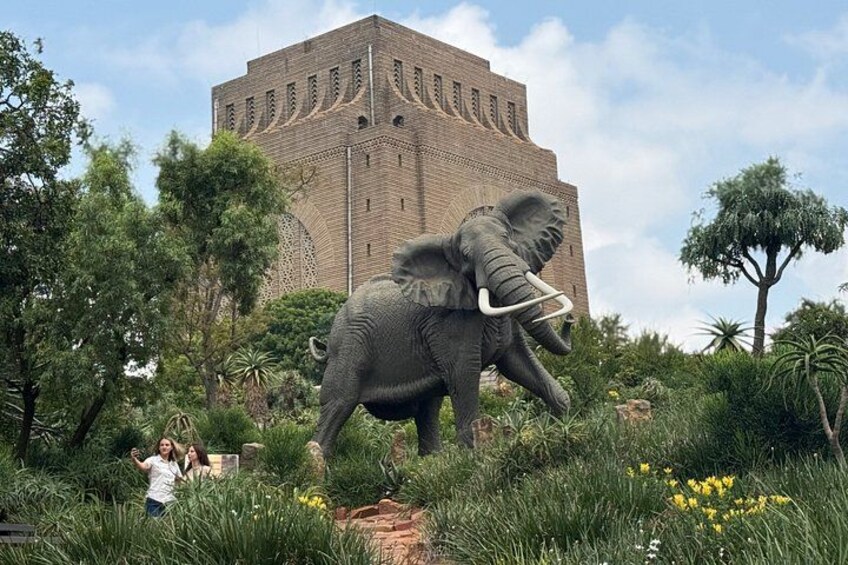A large elephant statue in a garden with a building in the background. 5