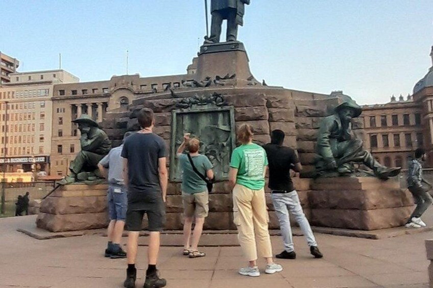 A group of people standing around a monument with statues. 1