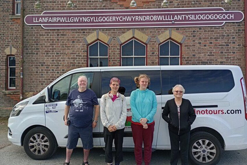 A white van parked in front of a brick building with a sign above it. 2