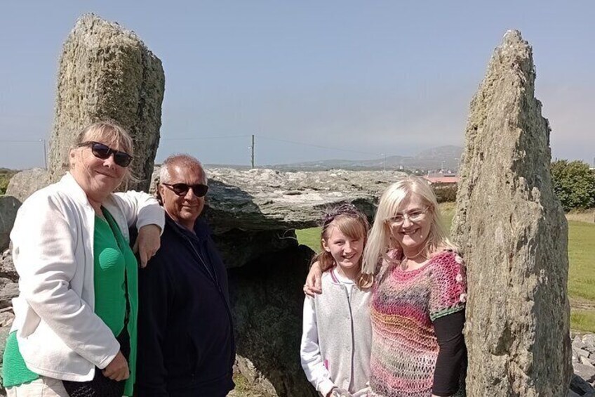 A group of people standing in front of stone structures with a coastal landscape in the background. 2