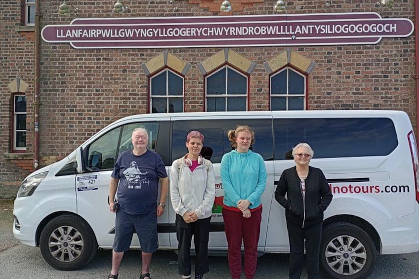 A white van parked in front of a brick building with a sign. 2