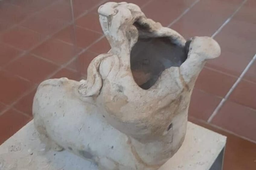 Eine weiße Keramikskulptur einer menschlichen Figur mit großem Kopf und kleinem Körper, präsentiert auf einem Sockel. 4