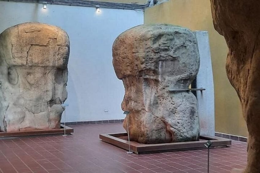 Zwei große Steinskulpturen von Menschenköpfen in einem Museum. 5