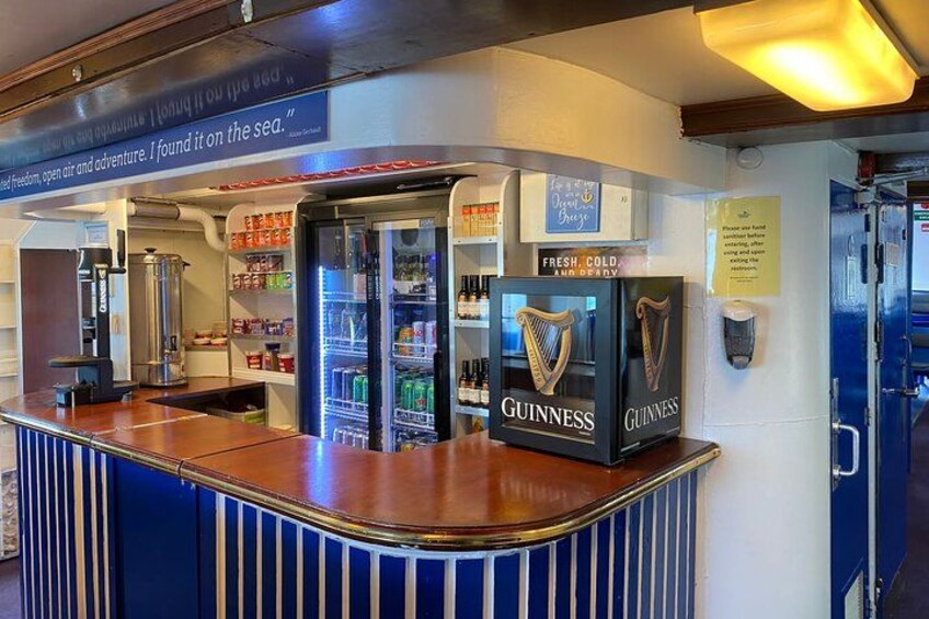 Een bar met een toonbank, een koelkast en een bord waarop staat 'Fresh Cold Guinness'. 3