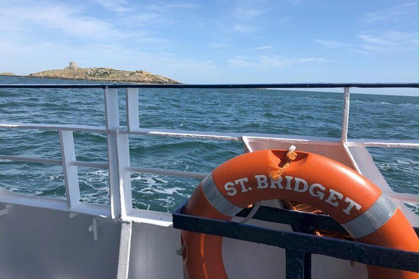 Una boya con la etiqueta 'ST. BRIDGET' en un barco, con una isla rocosa al fondo. 2