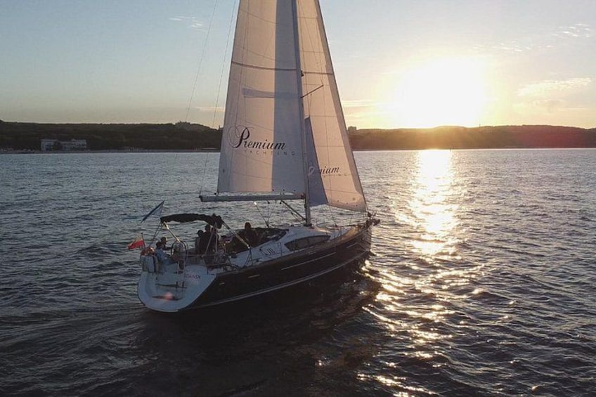 En segelbåt med namnet ”Premium” på stilla vatten under solnedgången. 2