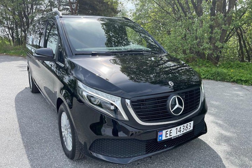 A black Mercedes-Benz SUV parked on a road with trees in the background. 2