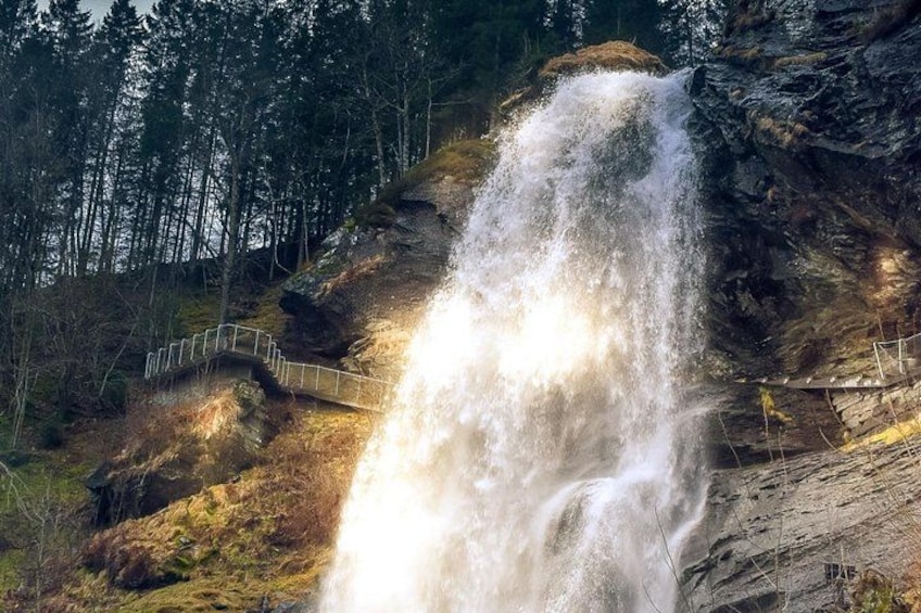 A waterfall cascading over a rocky cliff, surrounded by a forested area. 5