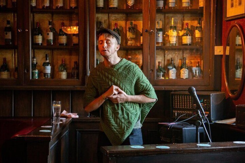Eine Person steht an der Bar, im Hintergrund Regale voller Flaschen. 5