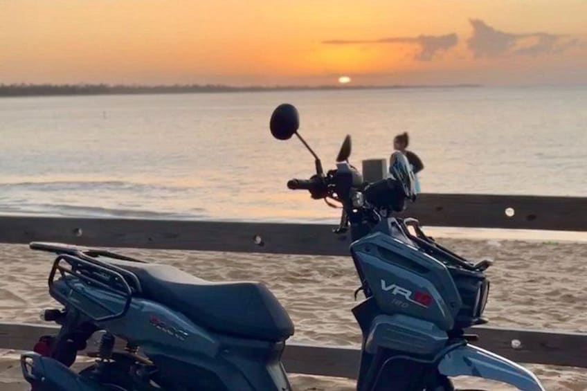Två motorcyklar parkerade vid vattnet under solnedgången. 1