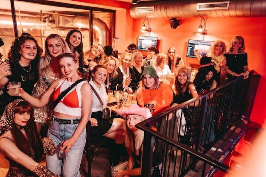 A group of people in a restaurant with orange walls and a staircase. 1