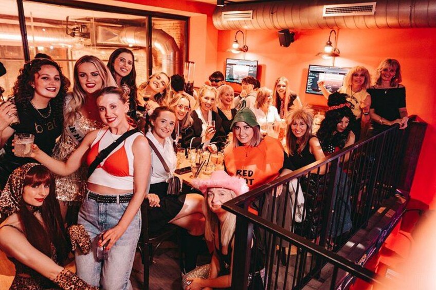 Eine Gruppe von Personen in einem Restaurant mit einer Treppe und orangefarbenen Wänden. 1