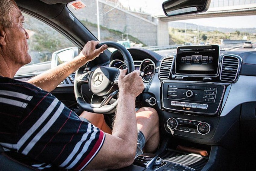En man som kör en Mercedes-Benz med en digital instrumentpanel och ett centralt infotainmentsystem. 5