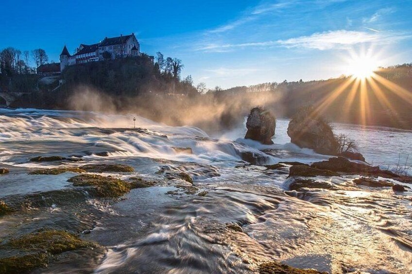 A river with rocks, a castle, and the sun setting. 3
