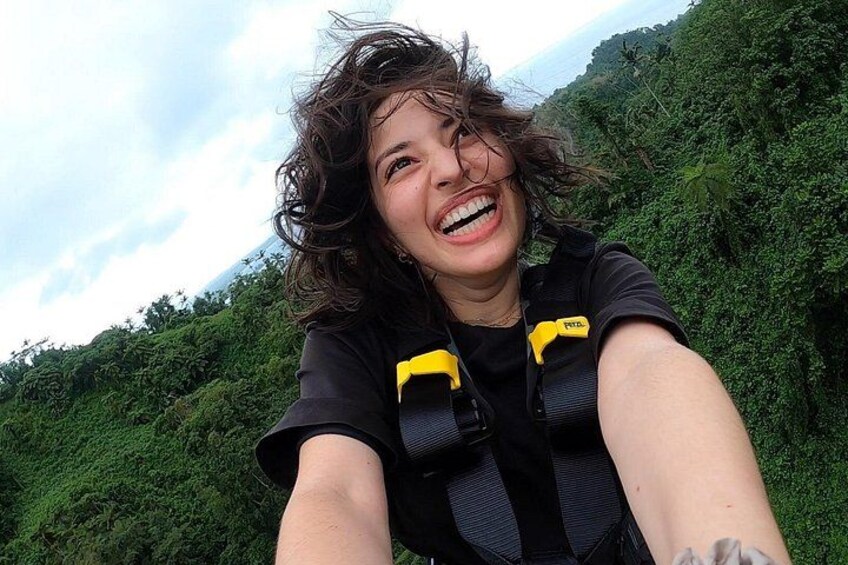 Eine Person mit gelb-schwarzer Schwimmweste macht ein Selfie vor einem üppigen, grünen Wald. 1