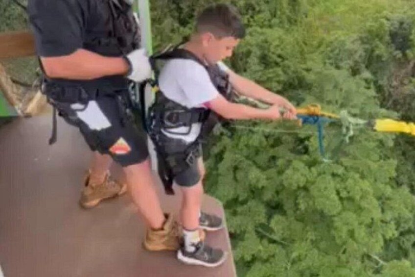 Eine Person ist beim Ziplining unterwegs und trägt dabei Schutzkleidung. Im Hintergrund ist bewaldetes Gelände zu sehen. 4