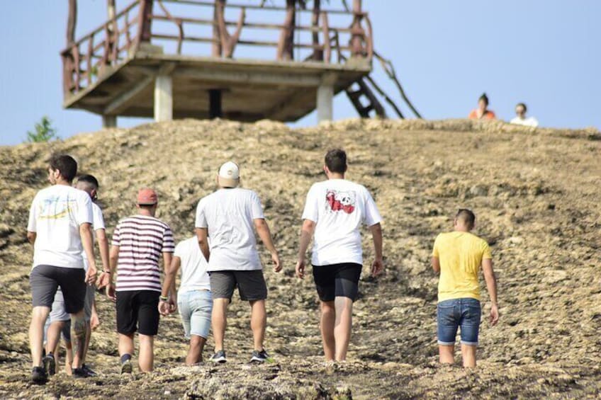 Un grupo de personas caminando por una colina arenosa hacia una estructura de madera. 4