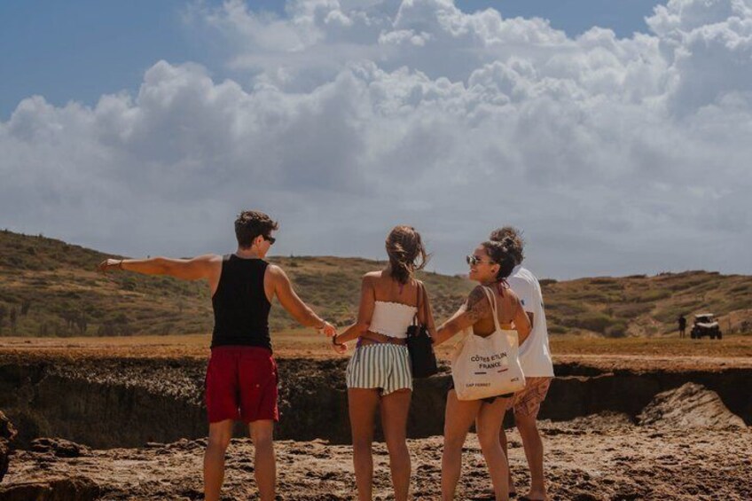 Three people holding hands on a beach with a vehicle in the background. 2