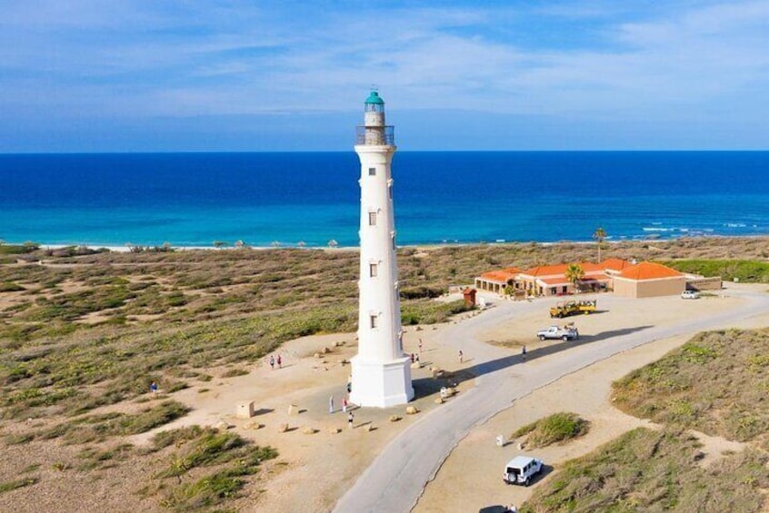 A lighthouse, a building, and a beach with people and vehicles. 3