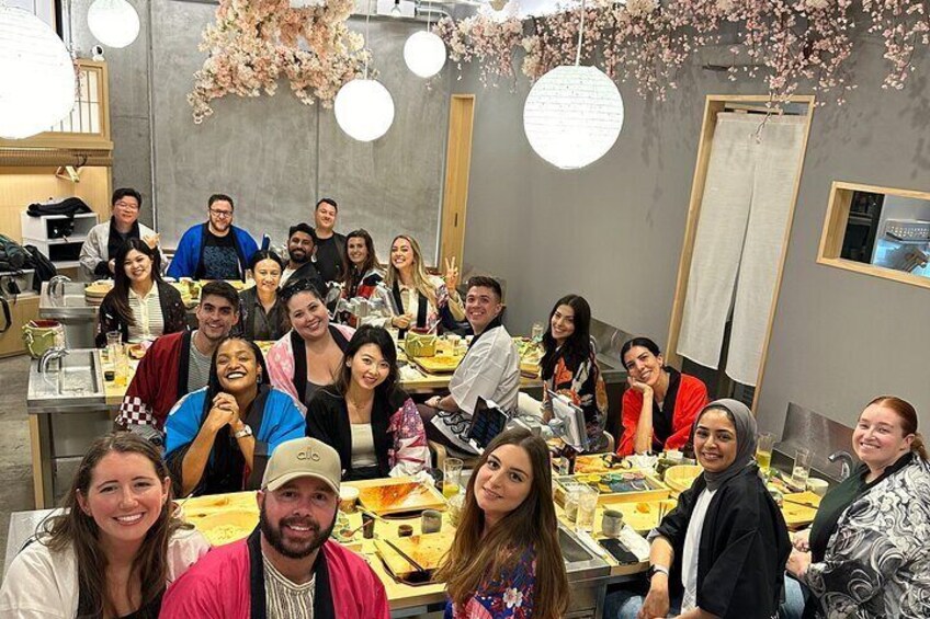 A group of people seated at tables in a restaurant with hanging floral decorations. 1