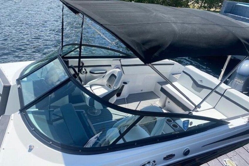 A boat's interior with a steering wheel, windows, and a canopy. 4