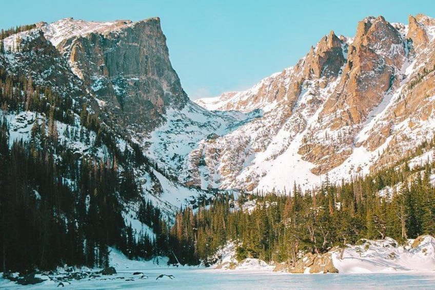 A snow-covered mountain range with dense forests and a clear sky. 5