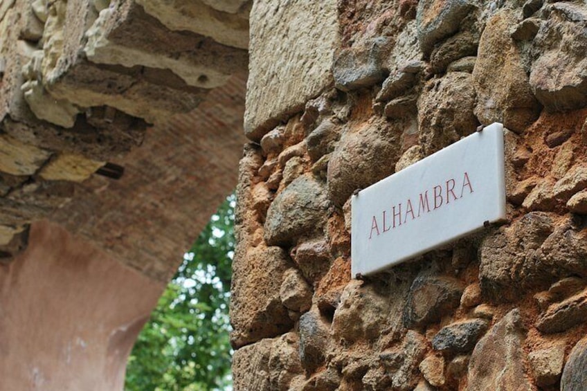Un muro de piedra con un letrero que dice 'ALHAMBRA'. 4
