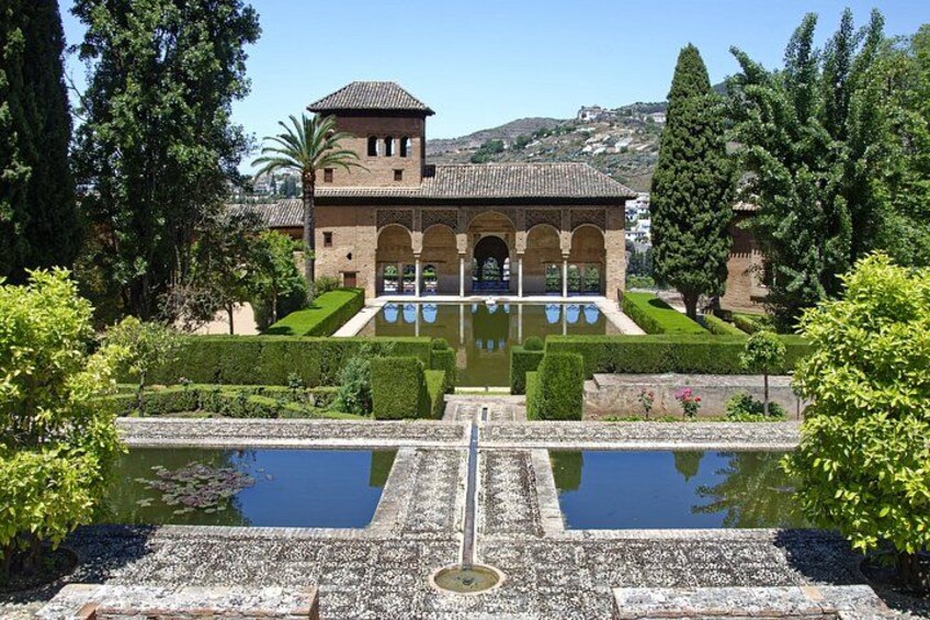 Un edificio histórico con un patio, una fuente y jardines cuidados. 3
