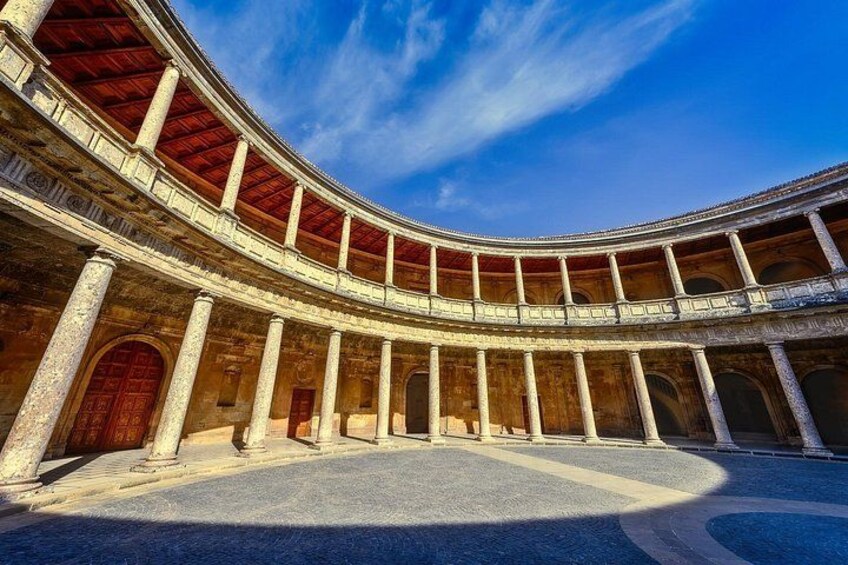 A large, circular building with multiple levels of arches and columns, under a clear blue sky. 2