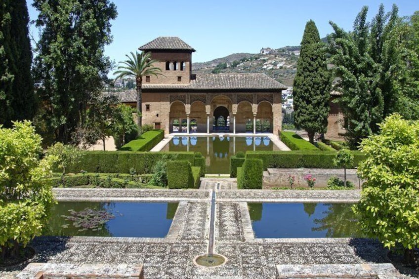 A historic building with a courtyard, a reflecting pool, and well-manicured gardens. 5