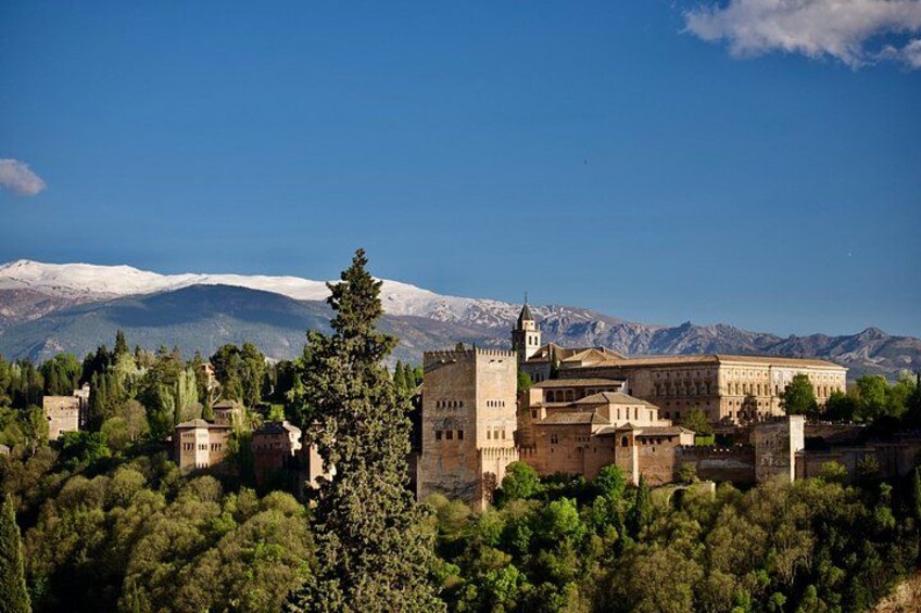 A historic castle with a tower, surrounded by trees and mountains in the background. 3