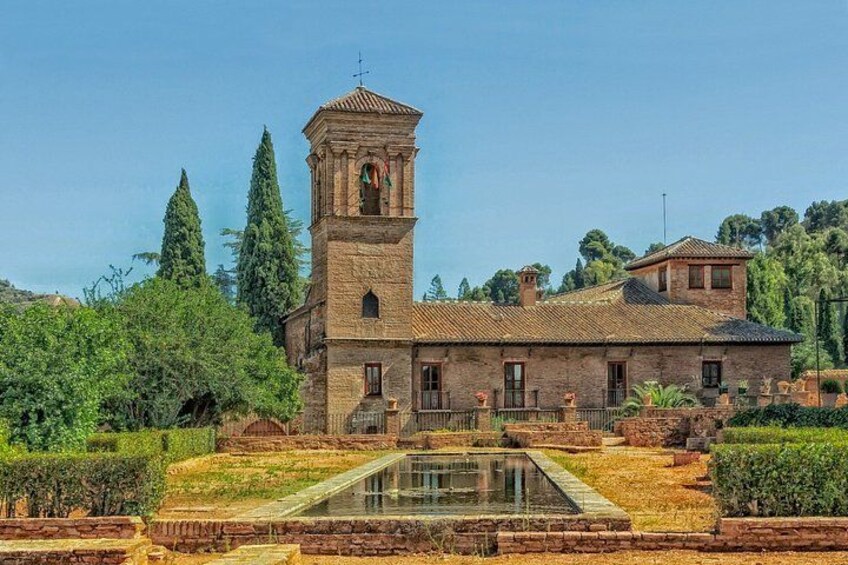 A historic building with a bell tower, surrounded by a garden with a reflecting pool. 4