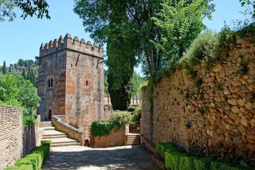 A stone castle with a tower, a stone wall, and a pathway leading to it. 2