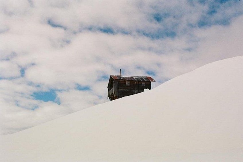 Ein einzelnes Häuschen auf einem schneegebdeckten Hang unter einer bewölkten Himmel. 3