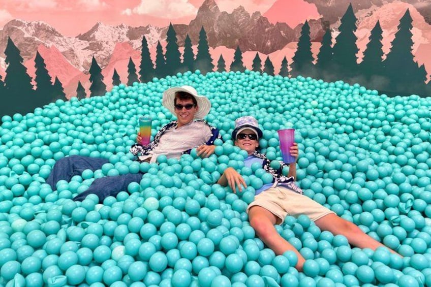Two people lying in a ball pit with a mountainous landscape in the background. 2
