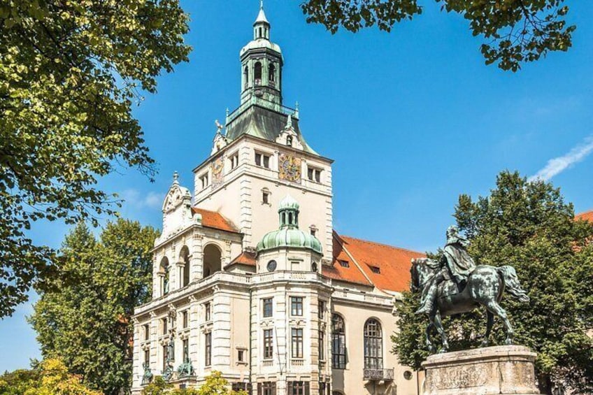 A historic building with a clock tower and a statue of a horse. 2