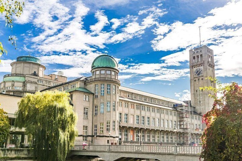 A historic building with a clock tower, domed structures, and a bridge. 4