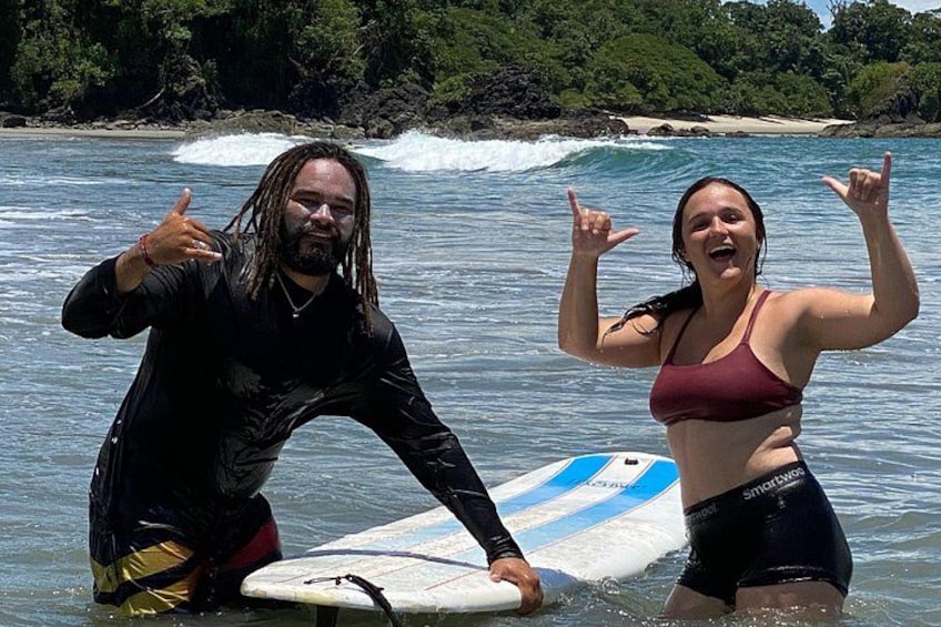 Two people in water with a surfboard, ocean waves, and a beach in the background. 1