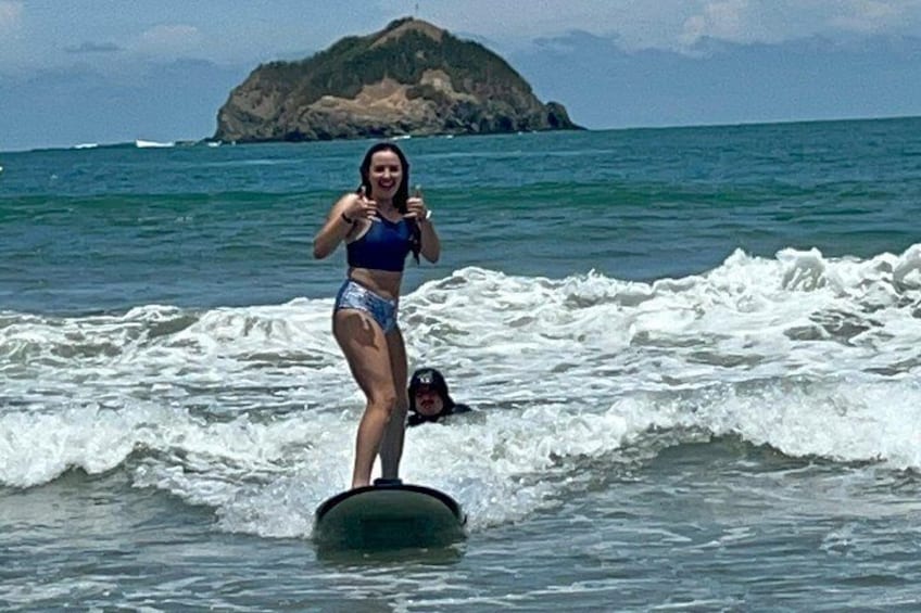 A person surfing on a wave with a mountainous island in the background. 5